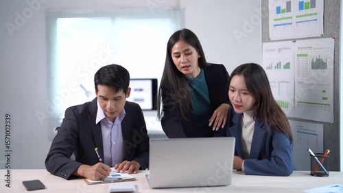Three people are sitting at a table with a laptop in front of them. They are discussing something important