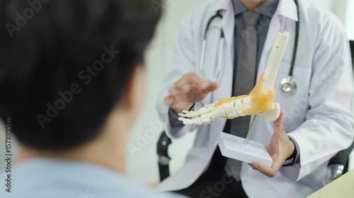 Doctor explaining foot joint anatomy to patient using realistic bone model during orthopedic consultation, healthcare professional demonstrating bone structure and discussing foot or ankle condition.
