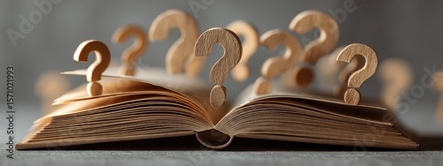 Open book with wooden question marks rising from its pages, suggesting unanswered questions or search for knowledge