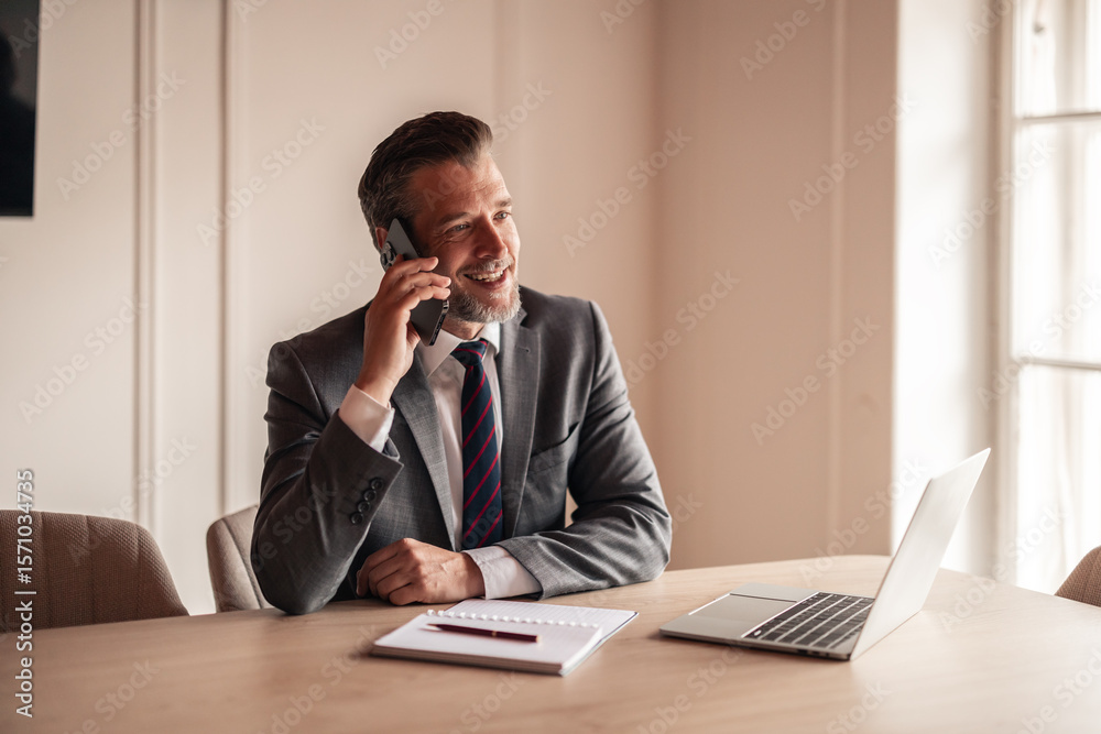 Professional Businessman Using Smartphone and Laptop in Bright Office Setting Professional Businessman Using Smartphone and Laptop in Bright Office Setting