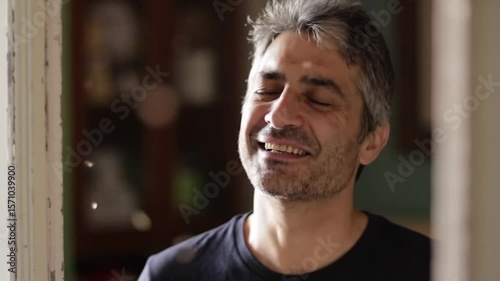 Man closing his eyes and smiling as breeze passes through an open window