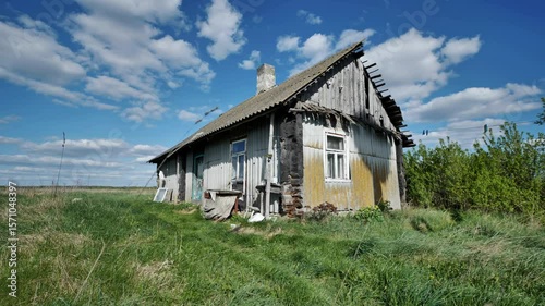 Old abandoned wooden house falling apart in slavic village under blue sky