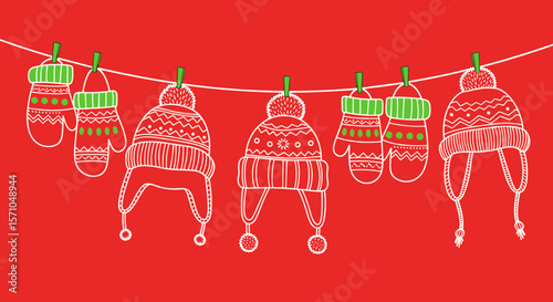Colorful winter hats and mittens hanging on a line against a red background