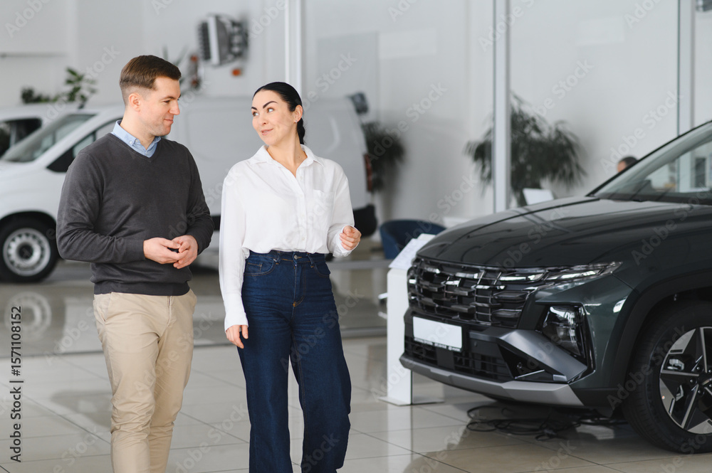 The successful visit to the dealership. Happy young couple chooses and buying a new car for the family The successful visit to the dealership. Happy young couple chooses and buying a new car for the family