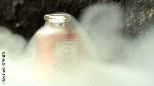 Steam rising from the poison bottle as the cork pops off creating a dramatic and eerie effect with toxic fumes escaping into the air