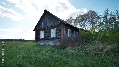 Old wooden abandoned house in slavic village surrounded by green grass and trees