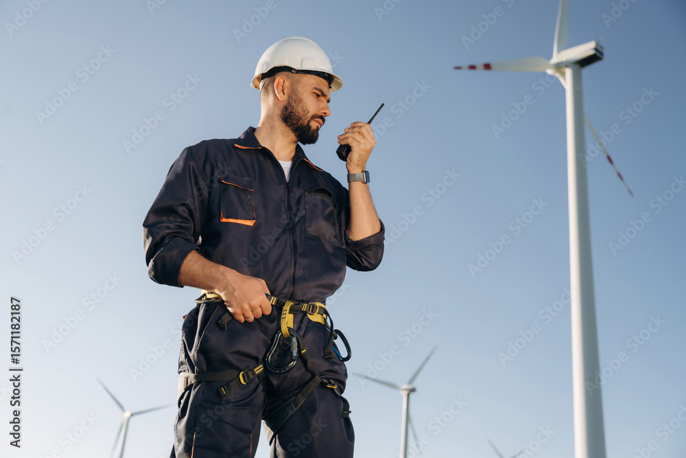 Fototapeta premium Communicating by walkie talkie. Engineer in field checking on wind turbine production