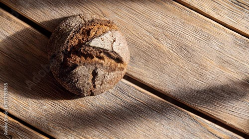 Artisan bread loaf on rustic wooden surface with shadows