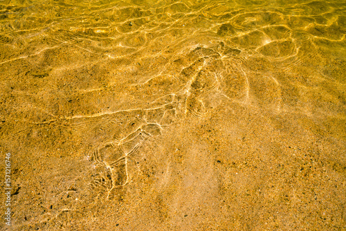 Close up shot of water rippling over yellow sand