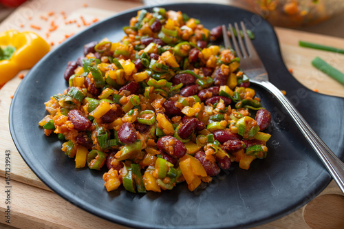 Delicious vegan salad with red lentils, kidney beans and yellow bell peppers on a plate