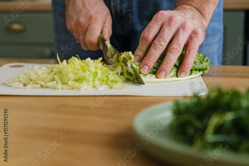 Photos Handsome bearded man is preparing green fresh vegan salad in the kitchen at home