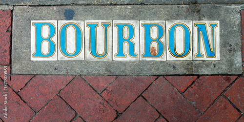 Old ceramic street sign on a the pavement in Bourbon street, New Orleans French Quarter, Louisiana
