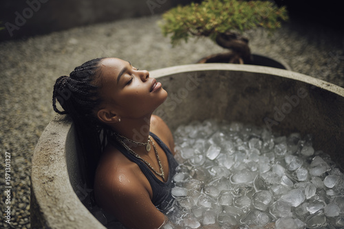 Afro-American woman in an ice tub with campsite in the mountains in the background