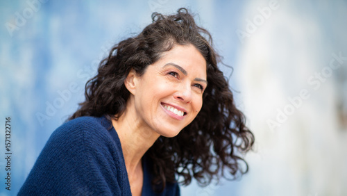 Obraz na płótnie Close-up of a joyful woman with curly hair, smiling outdoors