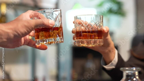 A man and woman clink glasses of whiskey together.