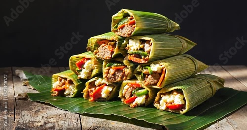 A stack of savory food wraps, nestled in vibrant green leaves, arranged on a rustic wooden surface