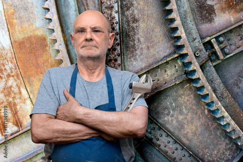 Experienced Engineer Posing with Wrench Against Industrial Machinery Backdrop
