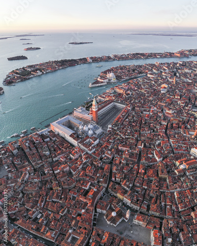 Aerial view of the terracotta rooftops cascading down towards the iconic St. Mark's Square and its towering campanile, Venice, Veneto, Italy.