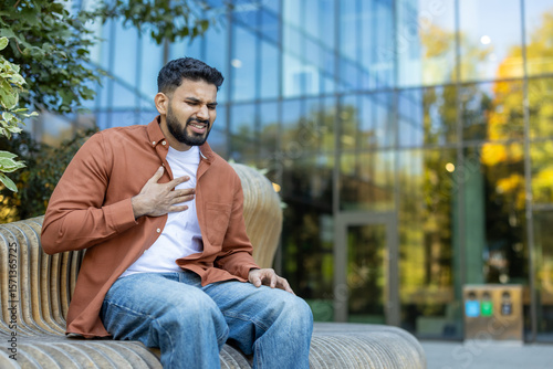 Εκτύπωση καμβά A man experiencing chest pain, sitting outdoors, likely having a health issue or heart attack, in a city setting
