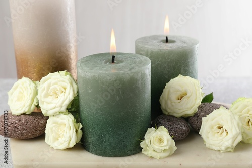 Burning candles, stones and rose flowers on table, closeup