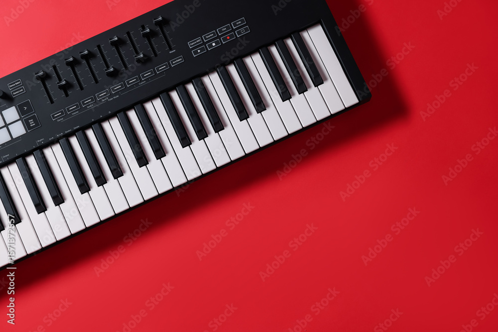 Fototapeta premium One portable MIDI keyboard on red background, top view. Space for text