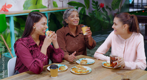 Obraz na plátně Indian happy senior woman lady group sitting around table eat break time tasty l