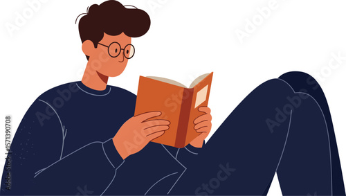 Young man reading book while relaxing in casual outfit with glasses and focused expression indoors