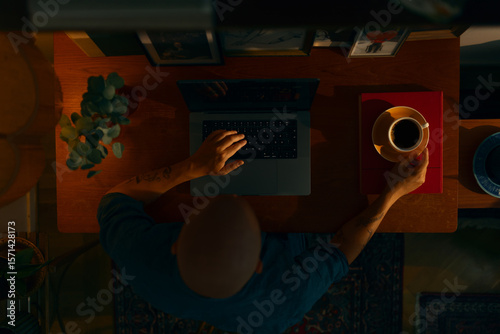 Portrait of a young caucasian man using a laptop sitting in a cosy living room, top view.
