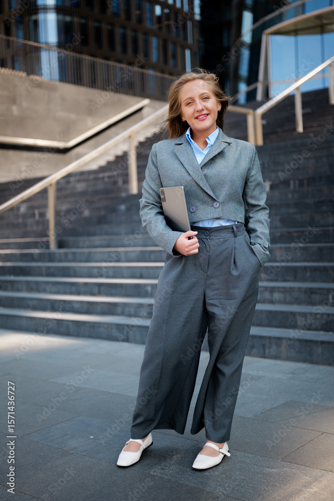 Confident professional poses on urban steps with laptop in hand during a sunny day Confident professional poses on urban steps with laptop in hand during a sunny day