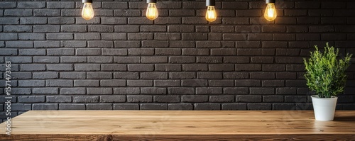 A modern wooden table against a black brick wall with hanging Edison bulbs and a small potted plant on the right side.
