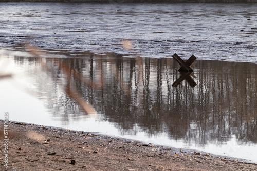 Iron anti-tank hedgehog in a dirty lake
