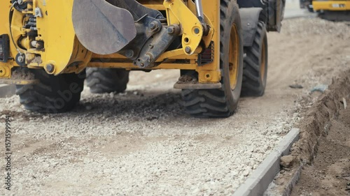 A busy construction scene showcasing heavy machinery actively paving and creating a new gravel road