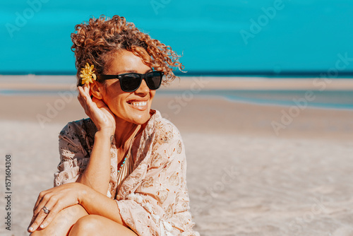 Portraits of a joyful curly-haired woman with sunglasses enjoying a summer day at the beach. Happy vacation vibes, freedom, healthy lifestyle, solo travel, outdoor fun and relaxed destination mood