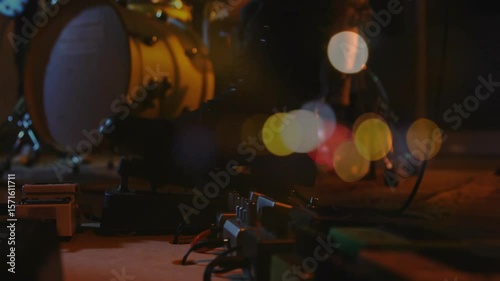 Camera shifting focus over pedal board cables causing stage lights pulsating to showcase gear mood