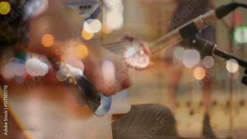 Musician placing guitar and plucking arpeggio pattern while microphone capturing performance