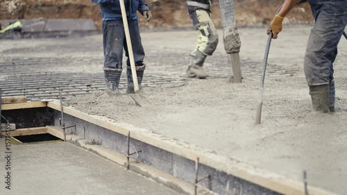 On a busy construction site, workers are pouring and leveling concrete to create a solid foundation for the project