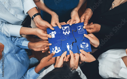 Fotografie This image captures the essence of collaboration and management as hands come together to connect puzzle pieces, symbolizing teamwork and strategic business development