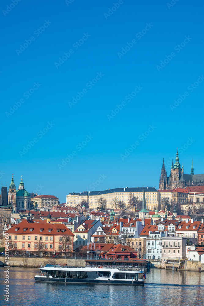 Fototapeta premium Prague, Czech Republic. Modern electric Boat tour vessel navigating the Vltava River, with historic riverfront buildings