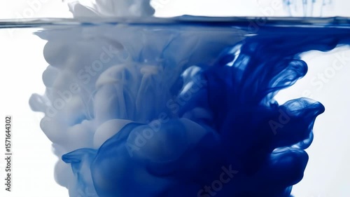 Ultra-slow-motion of milk-white and deep blue ink swirling in clear water, smooth organic clouds and tendrils with fine texture details on bright clean backdrop