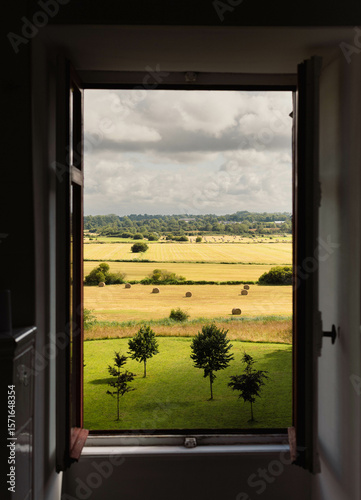 Countryside view of hay bales and tress through a window