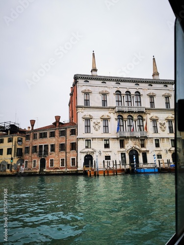 Historic buildings lining the canal in Venice during a cloudy day, showcasing classic architecture and reflections in the water