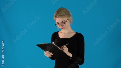 Dissatisfied model wearing glasses writing on piece of paper. Blonde woman with makeup wrinkles eyebrows crossing out notes slow motion