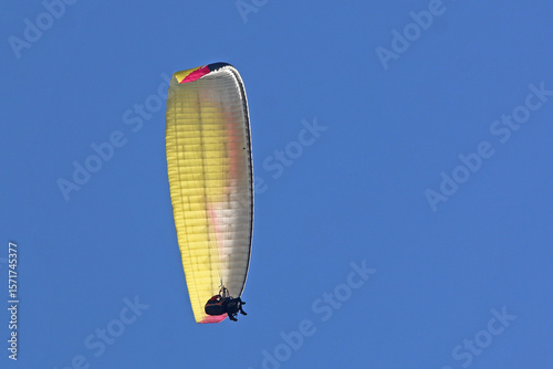 Tandem Paraglider flying in a blue sky	