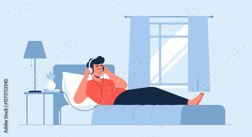 Man Relaxing On Bed Listening To Music With Headphones In The Bedroom