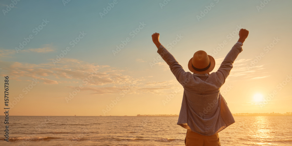 Fototapeta premium A powerful image of a man raising his arms in triumph against a vibrant sunset over the ocean, symbolizing success, freedom, and the joy of achievement in a beautiful, natural setting