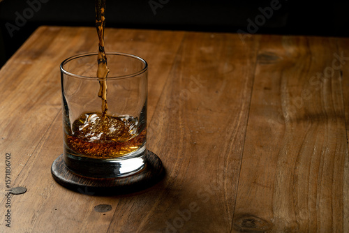 glass of whiskey being poured on a wooden table