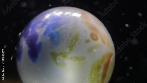 Close up shot of a spherical object with blue and yellow patterns and water droplets around it