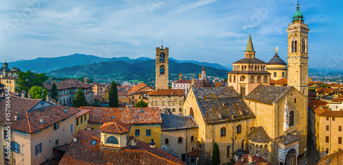 Aerial view of Bergamo’s Città Alta in Italy with terracotta rooftops, historic churches, and mountain backdrop on a clear day