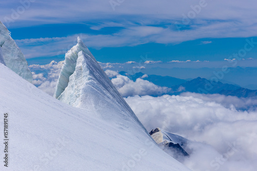 Mont Blanc ascent views on snow-covered ridge, surrounded by alpine peaks under clear and cloudy sky. High-altitude mountaineering, glacier terrain, mountain landscape outdoor expedition in Alps