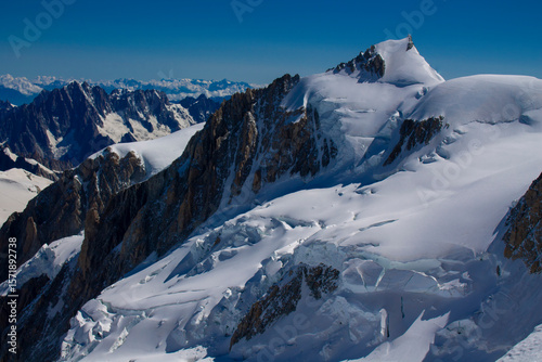 Mont Blanc ascent views on snow-covered ridge, surrounded by alpine peaks under clear and cloudy sky. High-altitude mountaineering, glacier terrain, mountain landscape outdoor expedition in Alps